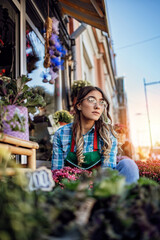 Young adult woman working in city street flower shop or florist. Small business concept.