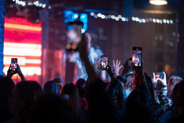 Person close up of recording video with smartphone during a concert.