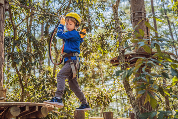 Happy child in a helmet, healthy teenager school boy enjoying activity in a climbing adventure park...