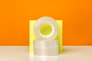 Adhesive sticky tape on white table against bright color background. Minimalistic, vivid colors. Office supplies.
