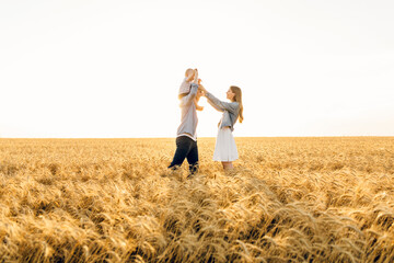 Happy family on a summer walk, mother, father and child walk in the wheat