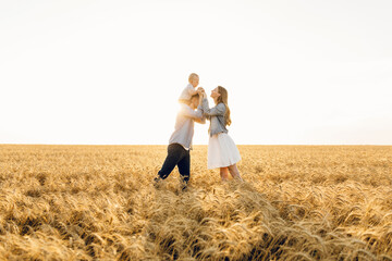 Fototapeta na wymiar Happy family on a summer walk, mother, father and child walk in the wheat