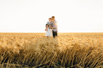 Naklejka na ściany i meble Happy family on a summer walk, mother, father and child walk in the wheat