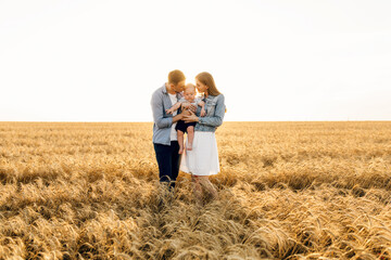 Happy family on a summer walk, mother, father and child walk in the wheat
