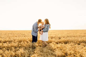 Happy family on a summer walk, mother, father and child walk in the wheat