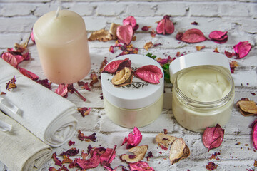 Two handmade cream jars decorated with bright rose petals.