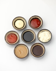 Set of colored sauces in Crockery. Variety of different sauces, mayonnaise, mustard, soy sauce, ketchup, Top view. Objects isolated on white background. Tasty food. Kitchen utensils.
