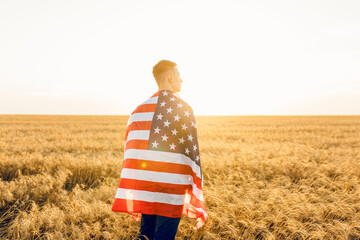 Young man holding American flag while standing on wheat field