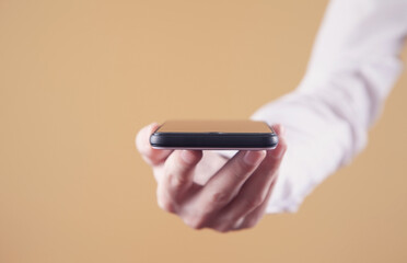 Man holding smartphone on yellow background. Technology concept