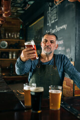 middle aged barman serving beer in pub