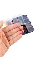 Male hand holds a silicone bait. Boxes with silicone baits in the background. Studio photo with objects isolated on white background.