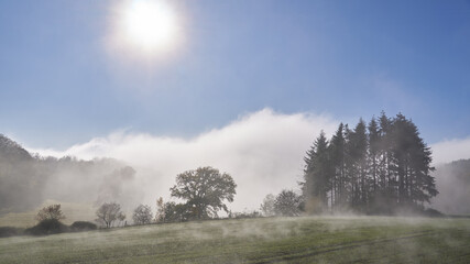 Stahlender Sonnenschein löst den Nebel über der herbstlichen Landschaft auf
