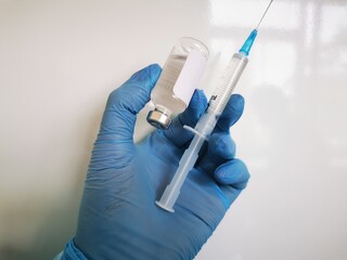 A doctor's hand in blue medical gloves takes an injection of a vaccine against coronavirus,...