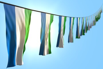 nice many Sierra Leone flags or banners hanging diagonal on rope on blue sky background with bokeh - any occasion flag 3d illustration..