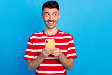 Photo of dreamy creative young man look empty space imagine post hold phone isolated on blue color...