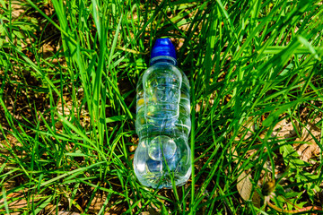Plastic bottle with the clear water in green grass