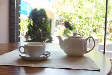 The table is set for tea. A teapot and a tea cup are placed on the table overlooking the terrace