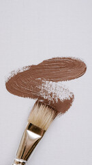 Brown paint smear and brush on white background