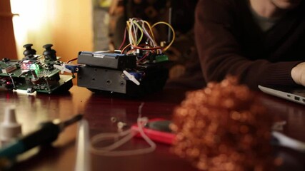 DIY, the machine on electronic control. Home experiments, robotics, smart engineer. a man works behind a laptop. Various devices and tools for creating electronic devices. Motherboard, soldering iron