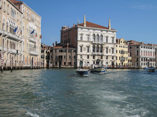 Venice old city grand canal with gondolas and boats. Romantic swimming in the morning. Comfotrable transportation to ancient historic hotel. Scenic Venetian scape on a sunny day.