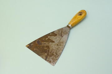 Old steel trowel scraper or spatula wooden handle isolated on blue background