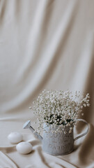 watering can for flowers with gypsophila on beige background, vintage