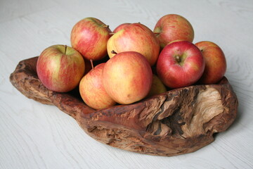 Mele rosse in un cesto marrone in radica di legno su sfondo bianco