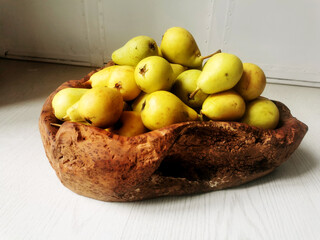 Pere gialle in un cesto marrone in radica di legno su sfondo bianco