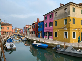 Boats docking and colorful houses in a canal street houses on Burano island, Venice, One unrecognizable people on the background.