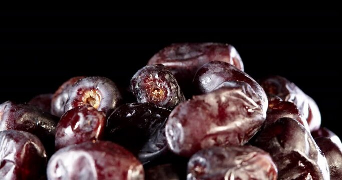 Fruit dates on a black background. Fresh dates slowly rotates. Close up food background. Gastronomy concept, organic food. Macro dates fruit.