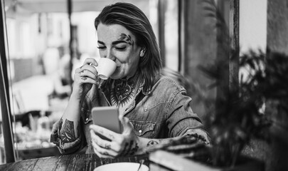 Girl with tattoo using mobile phone while outdoors at restaurant bar - Focus on face