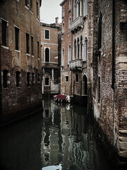 Dark picture, in the evening, of a boat in a small canal, in the water in Venice, Italy