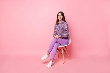 Full length photo portrait of cute girl sitting on white chair isolated on pastel pink colored...