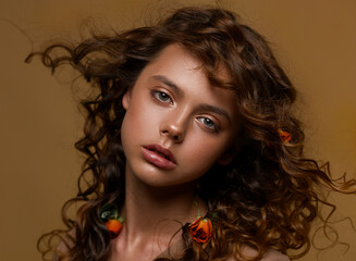 Portrait of a teenage girl. In the hair of the rose. Long brown hair. Curls develop in the wind....