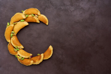 Ramadan kareem with qatayef arranged in shape of crescent moon. Traditional middle estern ramadan sweets. Iftar food concept. Top view, copy space © Veliavik
