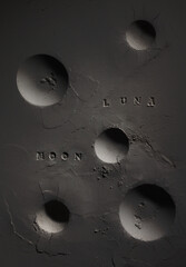 Dark surface of the moon with volcano craters. Print of the Spanish and English word 