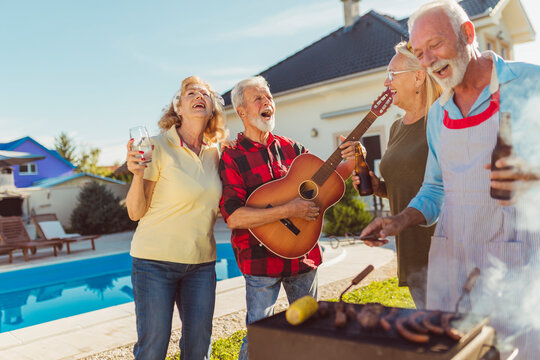 Senior people playing the guitar and singing at backyard barbecue party