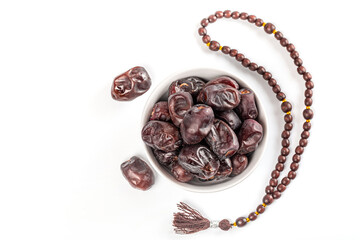 Muslim background for the holy month of Ramadan with dried dates in white bowl, and a rosary on white