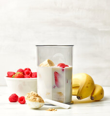 fresh banana, berries and milk in blender container