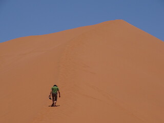 one man climbing up the dune 45 in sossusvlei