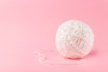 Wool yarn ball with woolen thread on pink background