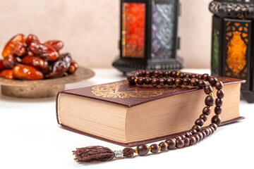 Muslim holiday of the holy month of Ramadan Kareem. Beautiful background with shining lantern, dried dates, prayer beads and quran book