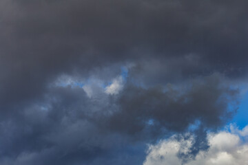 Fototapeta na wymiar Dark storm clouds on a bright blue sky. Sky patterns background 2021.