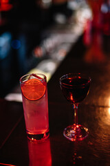 Gin and tonic and Manhattan cocktails on a bar desk.
