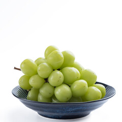 Beautiful a bunch of Shine Muscat green grape on a blue plate isolated on white background.