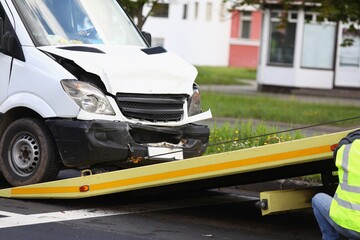 Wrecked white car pulling into tow truck