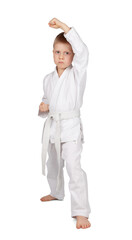 Little boy in kimono stands in karate rack isolated on white