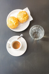 coffee couple with hot fresh espresso, two round cakes and glass of still water on grey surface. Vertical geometrical composition. Top view. raditional italian espresso ristretto. Coffe break