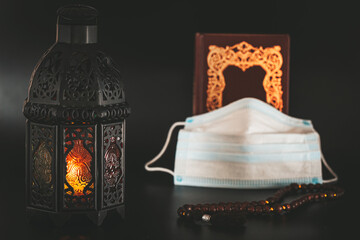 Muslim holiday of holy month of Ramadan Karim with shining lantern, book Koran and medical mask. Celebrating Holy month Ramadan in quarantine. Epidemic, coronavirus pandemic or covid-19 concept
