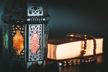 Muslim holiday of the holy month of Ramadan Karim on a dark background with a background with a shining lantern and a book of the Koran